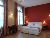 a bedroom with a large bed with red walls and windows at Hôtel Grand Monarque in Azay-le-Rideau