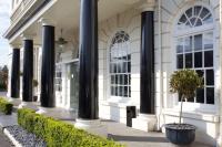 a white building with black columns and bushes at London Croydon Aerodrome Hotel, BW Signature Collection in Croydon