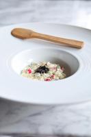 a white bowl of oatmeal with a wooden spoon at PM & Vänner Hotel in Växjö