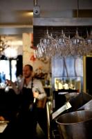 a man standing in a kitchen with glasses on the wall at PM & Vänner Hotel in Växjö