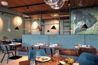 a dining room with tables and chairs and lights at TUI BLUE Montafon in Schruns-Tschagguns