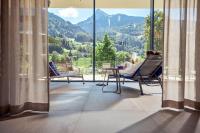 a woman sitting in a chair on a balcony looking out at the mountains at TUI BLUE Montafon in Schruns-Tschagguns