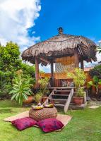 a gazebo with a table and some pillows in the grass at Red Garden Resort in Eluan