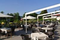 Un patio al aire libre con mesas, sillas y sombrillas. en Dei Hotel Schönblick, en Velden am Wörthersee