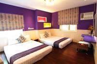 two beds in a hotel room with purple walls at Xing Ji Hotel in Kenting