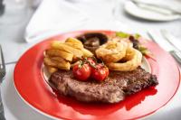een rood bord met biefstuk, uienringen en tomaten bij St James Hotel in Grimsby
