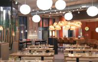 Un restaurante con mesas y sillas de madera y luces. en Ski-Inn RukaValley, en Ruka