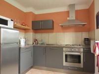 a kitchen with stainless steel appliances and an orange wall at Holiday Home with Garden Heating Barbecue in Butgenbach
