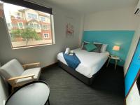a bedroom with a bed and a chair and a window at Nomads St Kilda in Melbourne