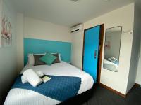 a bedroom with a blue and white bed and a mirror at Nomads St Kilda in Melbourne