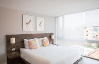 a white bedroom with a large bed and a window at Urban Heights Bogota in Bogotá