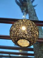 una lampada dorata appesa a una finestra con una palma di Hotel Pousada Casacolina a Búzios
