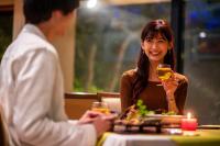 a man and woman sitting at a table with a glass of wine at Hotel Io Alpheratz in Kasama