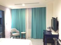 a hotel room with a bed and a desk and green curtains at Garden Hotel in Taichung