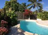 a swimming pool in a yard with trees and flowers at Villa Acajou in Saint-François