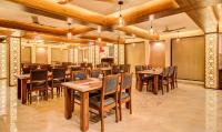 Un comedor con mesas y sillas de madera. en Opulence Inn - 500 Meters From Railway Station, en Udaipur