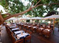 a restaurant with tables and chairs and umbrellas at UNAHOTELS Club Hotel Ancora in Stintino