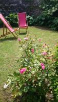 a pink chair sitting next to a bush with pink roses at Maison de 3 chambres avec vue sur la mer jardin clos et wifi a Regneville sur Mer a 2 km de la plage in Regnéville-sur-Mer