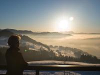 a person sitting on a bench looking at the sunrise at Wellnesshotel Linde in Sulzberg