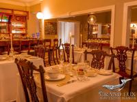 a dining room with a table with plates and glasses at Grand Lux Boutique Manor in Hermanus