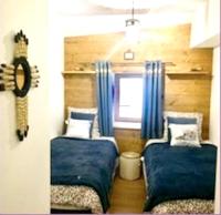 a bedroom with two beds and a window with blue curtains at Appartement de 4 chambres avec jardin clos et wifi a Le Monetier les Bains in Le Monêtier-les-Bains