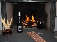 a bottle of wine and two glasses on a table with a fireplace at Casa Di Angeli in Corbara