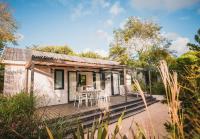 a cottage with a table and chairs on a wooden deck at Le Phare in Les Portes