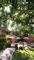 a patio with tables and umbrellas in a park at Yaang Come Village Hotel in Chiang Mai