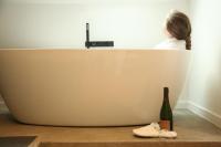 a woman sitting in a bath tub with a bottle of wine at B&amp;B Leonie in Alveringem