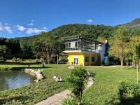 a house with a yellow house with a pond at Tree Lake B&amp;B Hualien in Shuhu
