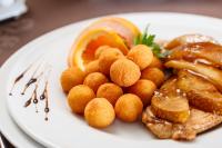 a plate of food with meat and oranges on it at Hotel O3zone in Băile Tuşnad