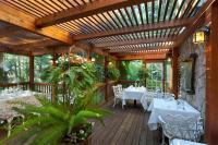 un patio con mesas blancas y sillas en una terraza de madera en Narrow Gauge Inn, en Fish Camp
