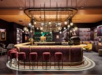 a bar with pink stools and a large chandelier at Naumi Studio Wellington in Wellington