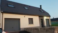 a house with a black roof and two garage doors at Granne de Lin étage in Tourville