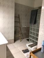 a bathroom with a shower with a toilet and a shelf at Sopraia Lodge in Les Abymes