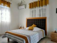 a bedroom with a large bed with yellow curtains at Sopraia Lodge in Les Abymes