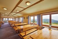 a row of tables and benches in a room with windows at Lyžařská bouda in Pec pod Sněžkou