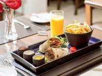 Una bandeja con un sándwich, papas fritas y jugo de naranja. en Mercure Sao Paulo JK, en São Paulo