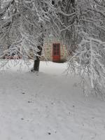 a building with a red door in the snow at Auverg&#39;Nature Chambre Cocon massage ayurvédique in Espinasse