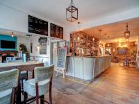 Un restaurante con un bar con sillas y un mostrador. en George &amp; Dragon Inn, en Chichester