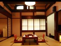 una sala de estar con una mesa y dos sillas en Ryokan Murayama, en Takayama