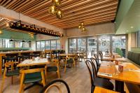 a restaurant with wooden tables and chairs and windows at Oaks Auckland Hotel in Auckland