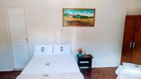 a bedroom with a white bed and a picture on the wall at Pousada Mama África in Conservatória