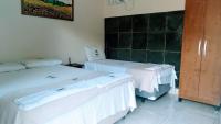 two beds in a room with white sheets at Pousada Mama África in Conservatória