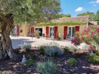 a house with red doors and a tree and flowers at Mas du Tilleul in Beaumes-de-Venise