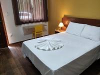 a bedroom with a white bed with a bow on it at Pousada Bougainville in Três Corações