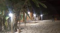 a man walking down a street at night with lights at Pousada Bougainville in Três Corações