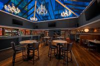 a bar with tables and chairs and chandeliers at George Limerick Hotel in Limerick