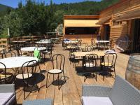 a deck with tables and chairs on a patio at Camping La Bernede in Rennes-les-Bains
