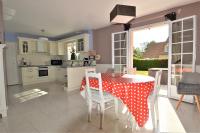 a kitchen with a table with a polka dot table cloth on it at Maison confortable séjour spacieux, belle terrasse avec grand jardin avec jeux extérieurs près Bayeux et Omaha Beach in Saonnet